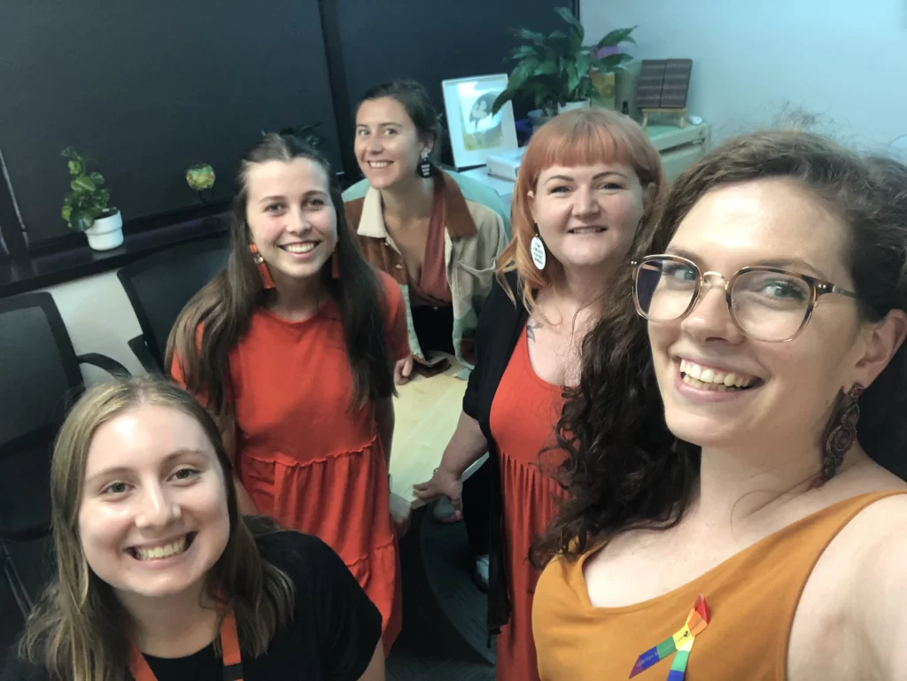 DVConnect team members wearing orange for the 16 Days of Activism. They are smiling and doing a selfie.