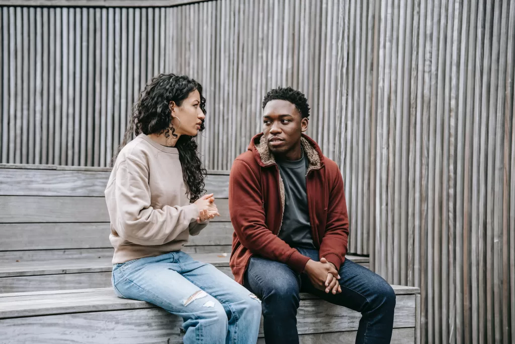 Two friends sitting and talking together. They have serious expressions on their faces.