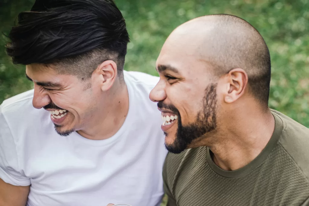 Two men smiling outside. They are very happy.