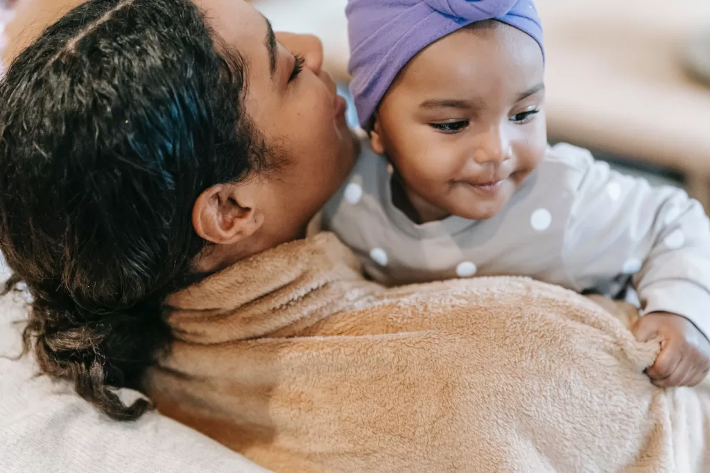 A brown woman and her child hug on a couch.